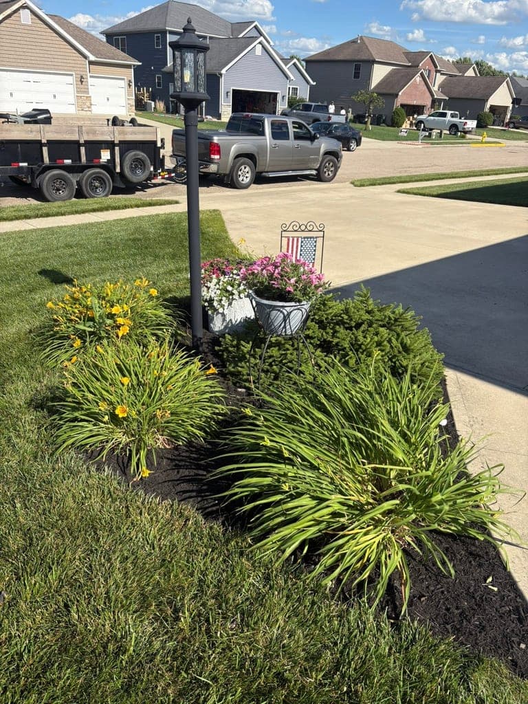 Front-yard flower bed freshly mulched with the Premier Landscape & Design trailer parked nearby